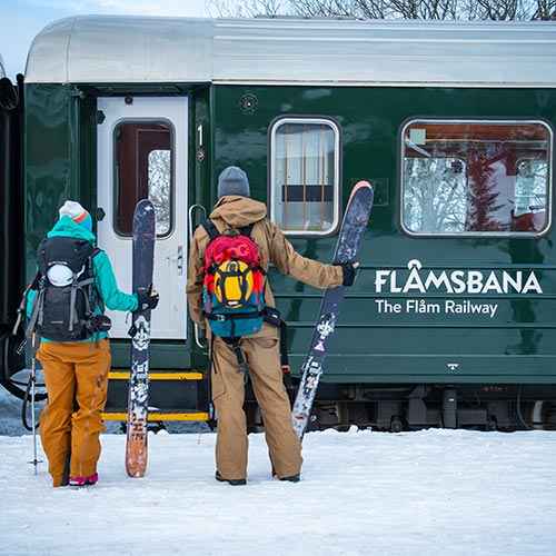 Zwei Personen mit Skiern vor Flåmbahn im Winter © Sverre F. Hjørnevik Fjellandsby Visit Norway